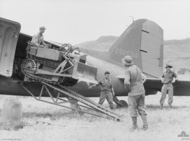 New Guinea. A bulldozer arrives for use on the Kaiapit strip, September 1943. The aircraft is C-47A 42-92034 of the 65th Troop carrier Squadron.