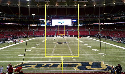 A football field as seen from behind one end zone. The tall, yellow goal posts mark where the ball must pass for a successful field goal or extra point. The large, rectangular area marked with the team name is the end zone.