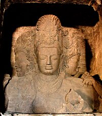 An ancient sculpture of Shiva at the Elephanta Caves, Maharashtra. 6th century CE Elephanta Caves Trimurti.jpg