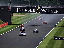 Foto av det soggy Silverstone-sporet med sikkerhetsbilen etterfulgt av Formel 1-biler