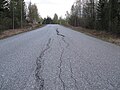 [1] Straße mit einem Fahrbahnbelag aus rissigem Asphalt