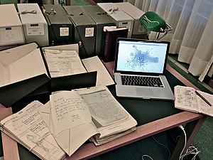 A laptop computer next to archival materials