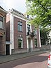 Herenhuis met gepleisterde middenpartij met kroonlijst, door siervazen bekroond balkon op consoles en dakkapel met gebogen fronton