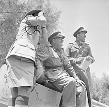 Lieutenant-General George Erskine (centre), observing operations against the Mau Mau. Erskine played a leading role in planning and carrying out Operation Anvil. Lieutenant General Sir George Erskine, Commander-in-Chief, East Africa (centre), observing operations against the Mau Mau.jpg