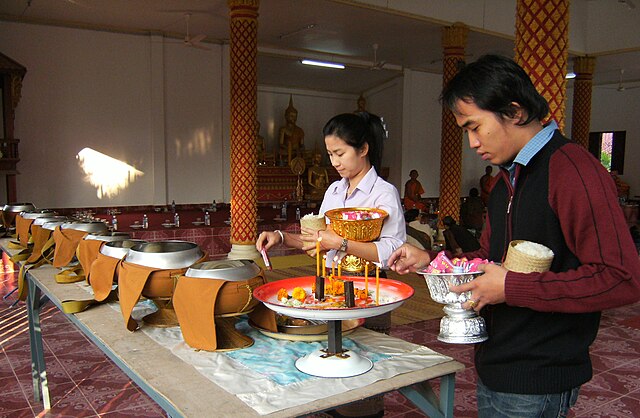 Offering of food to monks to make merit at a temple in Vientiane