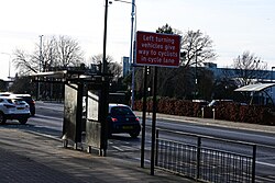 A bus stop on a cycle lane leading to the Mount Pleasant junction on Holderness Road in Kingston upon Hull, with a road sign warning motorists turning left to give way to cyclists in the lane.