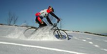 A mountain cyclist riding through a snowy field. Mtb in snow (crop).jpg