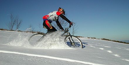 A mountain cyclist riding through a snowy field.