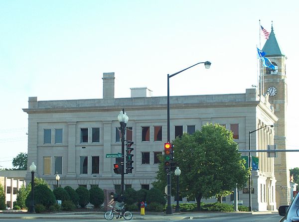 Neo-classical style Equitable Fraternal Union Building with the old City Hall clock tower behind it on S. Commercial St. (Wisconsin Highway 114).