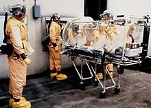 AIT members (with an older type of Racal suits) prepare to transfer a patient from a stretcher isolator into a BSL-4 medical care suite Racal Space Suits.JPG
