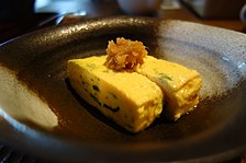 plate with two pieces of tamagoyaki, sliced crosswise to show spiral form