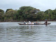 Ein Einbaum mit einer fünfköpfigen Familie auf dem bräunlichen Wasser des Flusses Rupununi.