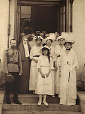 Fotografia a preto e branco que mostra um grupo de pessoas na entrada de um edifício.