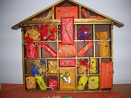 A house-shaped wooden shelf subdivided in compartments, with one decorated package in each compartment