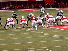 Miami's defense (left in white jerseys) lines up against Nebraska at Memorial Stadium in September 2014 Ameer Abdullah about to receive a snap (9-20-2014).jpg