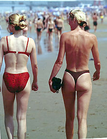 Some female clothing, such as the bikini or panties, show part of the female buttocks (woman on left). Thongs, in particular, leave almost all of the buttocks exposed (woman on right). Photo is of a beach in Holland, 1999. Bikini girls Holland beach 1999.jpg