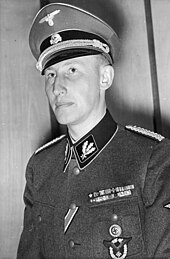 Černobílá fotografie, na níž je viděn muž v uniformě.
