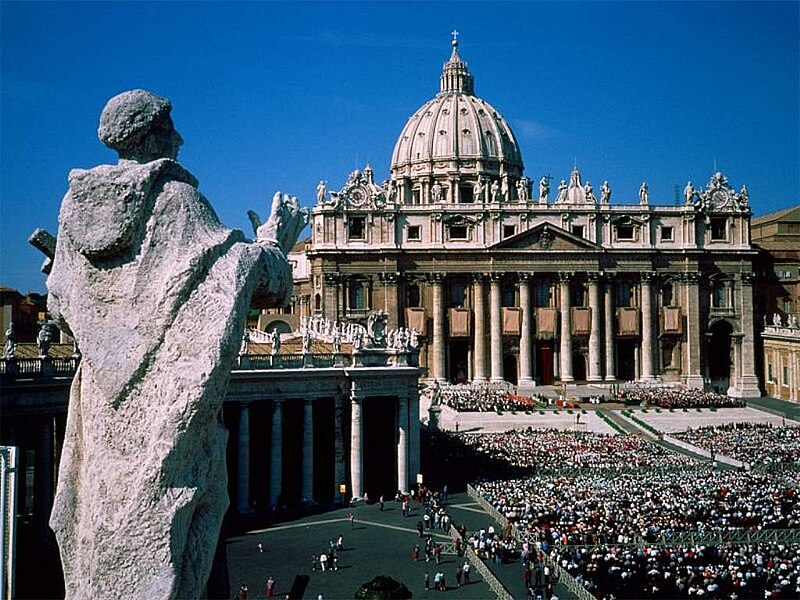 File:Crowd in front of a building with a dome photographed from behind a statue on an adjacent rooftop.jpg