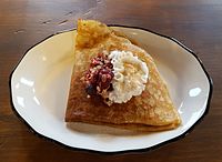 A sweet crêpe filled with oats, berries, and topped with whipped cream
