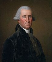 A man with white hair pulled into a braid wearing a black jacket, gray vest, and high-collared white shirt