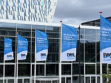 Flags at the entrance to the IWA World Water Congress & Exhibition, September 2022, at the Bella Center Copenhagen. International Water Association flags outside Bella Center Copenhagen Congress Center 2022.jpg