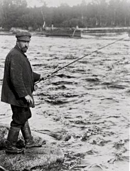 Writer Juhani Aho fishing in a river (1912).