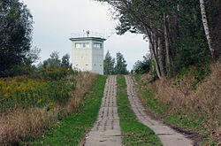 Twin rows of concrete tracks leading up a hillside to a watchtower, with trees on either side