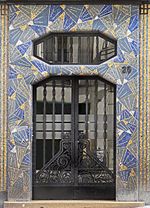 Fotografia di una porta d'ingresso di un edificio circondata da mosaici blu e oro.