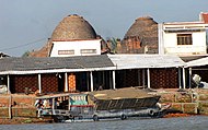 Brickmaking kilns, Mekong delta. The cargo boat in the foreground is carrying the rice chaff used as fuel for the firing.