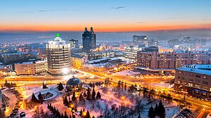 View of the part of Student Brigades Square and the intersection of Oktyabrskaya Highway, Serebrennikovskaya Street and Oktyabrskaya Street, as seen in 2017. In the lower left-hand corner, the part of the building of the Novosibirsk Globus Theatre is visible. In the center of the picture, you can see the building at 50 Kommunisticheskaya Street, popularly known as "Batman" and "Plug". Novosibirsk skyline in winter.jpg