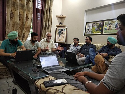 Indoor, a group of people, mostly men, sitting, discussing