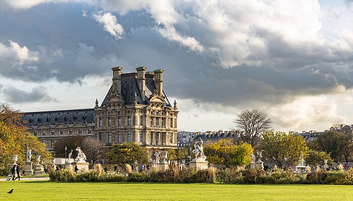 Sous un beau ciel gris, un magnifique bâtiment classique couronne un jardin de belles pelouses vertes, bosquets et statues.