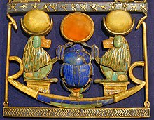 Le pectoral appartient à un grand collier. Dans le cadre, on observe une barque d'or incrustée de cornaline, de lapis et de feldspath, qui possède 2 pavillons en or sur lesquels sont assis 2 singes hamadryas (dieu Thot) se faisant face. Leurs têtes sont surmontées d'un croissant lunaire en argent soutenant l'image de la lune en or. Au centre, un scarabée en or et lapis-lazuli pousse devant lui la boule rouge du soleil faite de cornaline cerclée d'or.