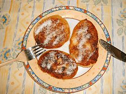 Quarkkäulchen saupoudrés de sucre, présentés dans une assiette.