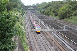 Roade cutting looking north from a pedestrian bridge with a Virgin Trains Pendolino travelling south on the fast lines with the Northampton loop lines on the right Roade cutting.JPG
