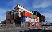 A stack of shipping containers covering the entrance to the theatre. The container wall. (46943835875).jpg