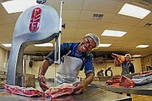 A smiling butcher slicing meat The happy butcher.jpg