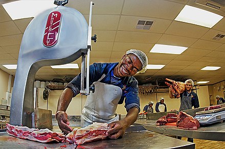 A butcher happily slicing meat