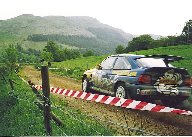 A Ford Escort RS Cosworth on a stage rally, driven by British driver Malcolm Wilson.