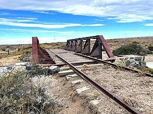 Puente ferroviario en desuso cruzando el arroyo parcialmente vandalizado.