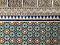 A detail of traditional Moroccan architectural elements: zeliij and arabesque plaster.