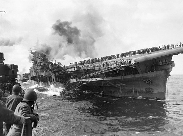 USS Franklin listing, with crew on deck, due to two armor piercing bomb hits penetrating the unarmoured flight deck, 19 March 1945. Total casualties, 