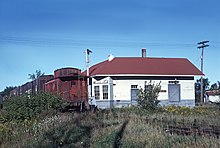 A Chicago and North Western freight train passes the junction in September 1964 CNW wayfreight passing the MILW station at Stiles Jct., WI in September 1964. (27224122431).jpg