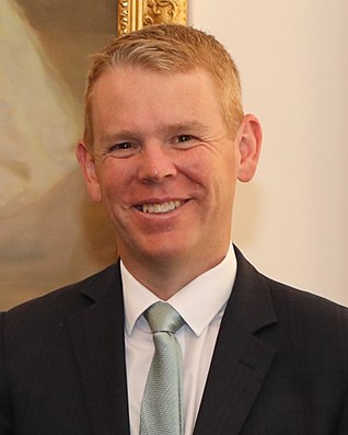 A smiling man wearing a dark business suit and tie