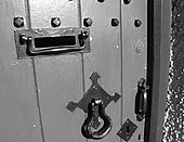 Front door of a house with typical door furniture: a letter box, door knocker, a latch and two locks