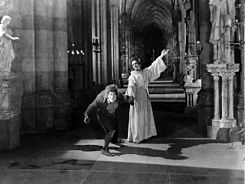 Dom Claude restrains Quasimodo from violence. Hunchback -Notre Dame 1923.jpg