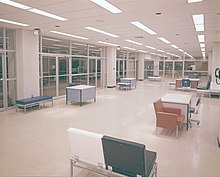 Tables and chairs in a modern interior room with glass interior walls and fluorescent lighting