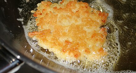 Potato latke frying in hot olive oil.