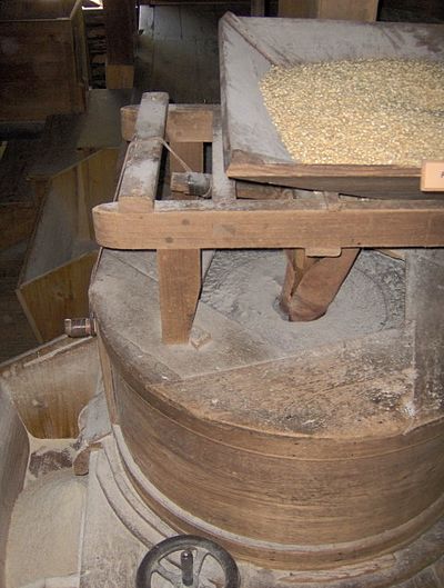 Grindstones inside Mingus Mill, in the Great Smoky Mountains of North Carolina. Corn is placed in a hopper (top right) which slowly feeds it into the grindstone (center). The grindstone grinds the corn into cornmeal, and empties it into a bucket (lower left). The grindstones are turned by the mill's water-powered turbine.