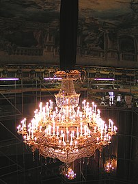 Riche lustre décoré de verreries, illumination par bougies ou lampes électriques en forme de bougies.
